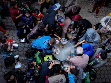 Walid al-Hattab Palestina membagikan sup kepada orang-orang yang membutuhkan selama bulan puasa Ramadhan di tengah pandemi COVID-19 di Kota Gaza (14/4/2021). (AFP/Mohammed Abed)