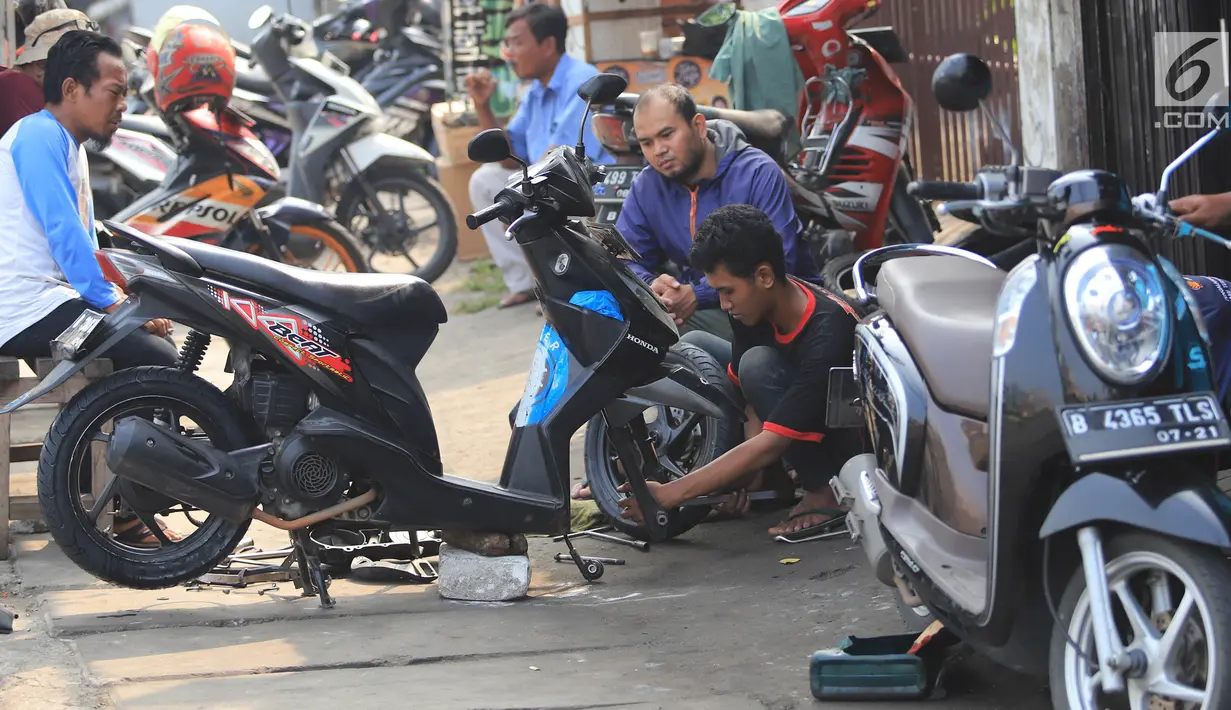 Mekanik memperbaiki motor di salah satu bengkel di Otista, Jakarta, Minggu (10/6). Calon pemudik motor mulai memenuhi bengkel guna menyervis atau mengganti suku cadang kendaraan sebelum digunakan untuk mudik Lebaran. (Liputan6.com/Angga Yuniar)