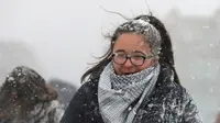 Seorang wanita melintasi jembatan milenium saat hujan salju turun di London (27/2). Cuaca ekstrem yang melanda sebagian wilayah Eropa menyebabkan warga dan wisatawan mengalami sakit dan beberapa meninggal akibat kedinginan. (AFP Photo/Daniel Leal-Olivas)