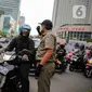 Petugas Satpol PP mengimbau pengguna kendaraan saat melakukan Pengawasan Pelaksanaan PSBB di kawasan Bundaran HI, Jakarta, Senin (13/4/2020). Petugas juga mengimbau mengatur posisi duduk dan pembatasan penumpang untuk kendaraan bermobil baik pribadi maupun angkutan umum. (Liputan6.com/Faizal Fanani)