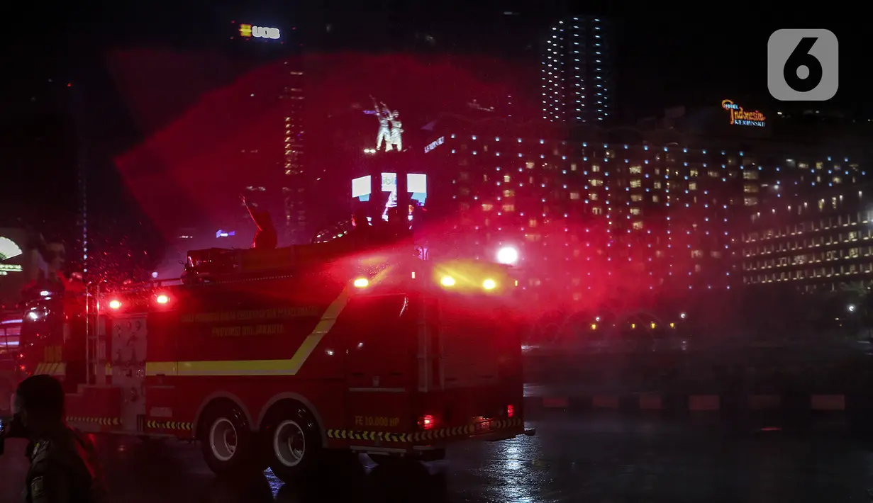 Petugas dari Dinas Penanggulan Kebakaran dan Penyelamatan DKI Jakarta menyemprotkan cairan disinfektan di sekitar Jalan Jenderal Sudirman-MH Thamrin, Jakarta, Kamis (31/12/2020). Jalan Jenderal Sudirman-MH Thamrin ditutup pada malam pergantian tahun 2020 menuju 2021. (Liputan6.com/Johan Tallo)