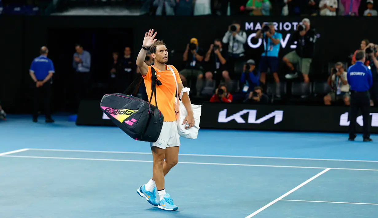 Petenis Spanyol Rafael Nadal melambaikan tangan saat meninggalkan Rod Laver Arena menyusul kekalahannya atas petenis Amerika Serikat Mackenzie McDonald pada pertandingan putaran kedua kejuaraan tenis Australian Open di Melbourne, Australia, Rabu (18/1/2023). Rafael Nadal harus tersingkir dari Australian Open 2023 setelah ia mengalami cedera dan kemudian takluk 4-6, 4-6, 5-7 dari petenis Amerika Serikat MacKenzie McDonald. (AP Photo/Asanka Brendon Ratnayake)