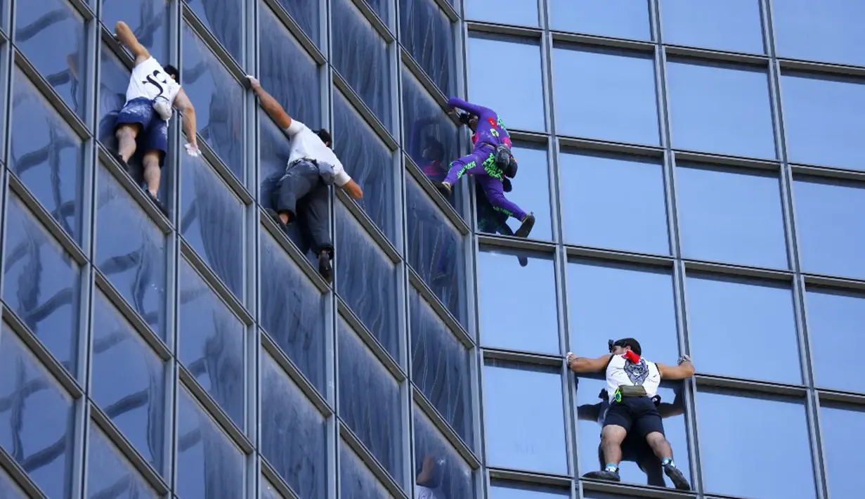 Pendaki Alain Robert (kedua kanan) atau Spiderman Prancis bersama Marcin Banot, Alexis Landot, dan Leo Urban memanjat Menara Total di La Defense, Paris, Prancis, 7 September 2021. Alain dengan tangan kosong memanjat menara setinggi 190 meter itu untuk menentang izin kesehatan. (THOMAS SAMSON/AFP)