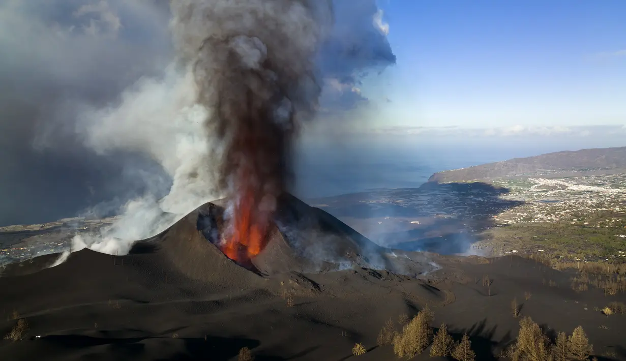 Lava mengalir dari gunung berapi di pulau Canary La Palma, Spanyol (30/11/2021). Beberapa lubang vulkanik baru dibuka di La Palma, melepaskan lava baru yang mengalir cepat menuruni punggung bukit dan akan memperluas dampak pada tanah yang dievakuasi , infrastruktur dan rumah. (AP/Emilio Morenatti)