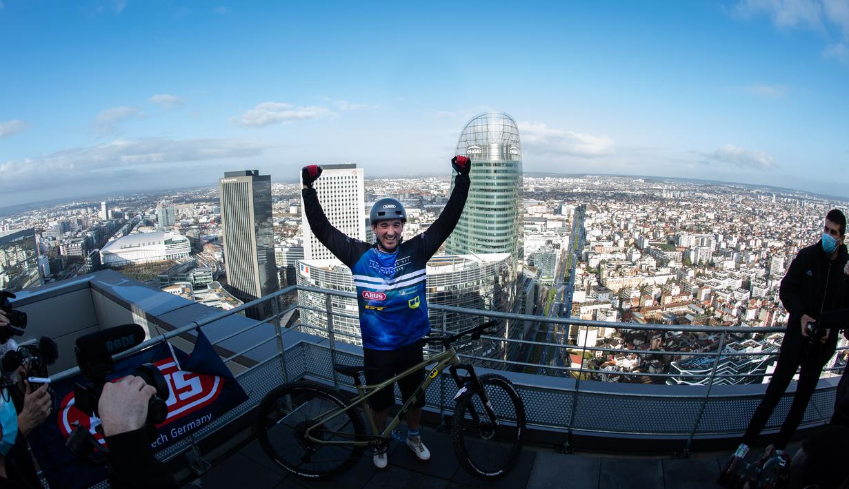 Pembalap sepeda asal Prancis, Aurelien Fontenoy, melakukan selebrasi usai mendaki 768 anak tangga dari 33 lantai gedung Trinity Tower di distrik La Defense, Paris, (17/1/2021). (AFP/Martin Bureau)