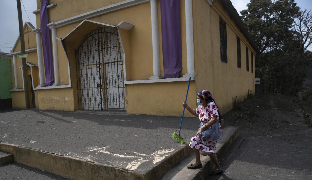 Lidia Esperanza Guzman beristirahat saat menyapu abu vulkanik Gunung Pacaya dari beranda Gereja Katolik di San Francisco De Sales, Guatemala, Selasa (23/3/2021). Abu juga menghujani sejumlah pesawat di kota itu hingga bandara internasional La Aurora ditutup. (AP Photo/Moises Castillo)
