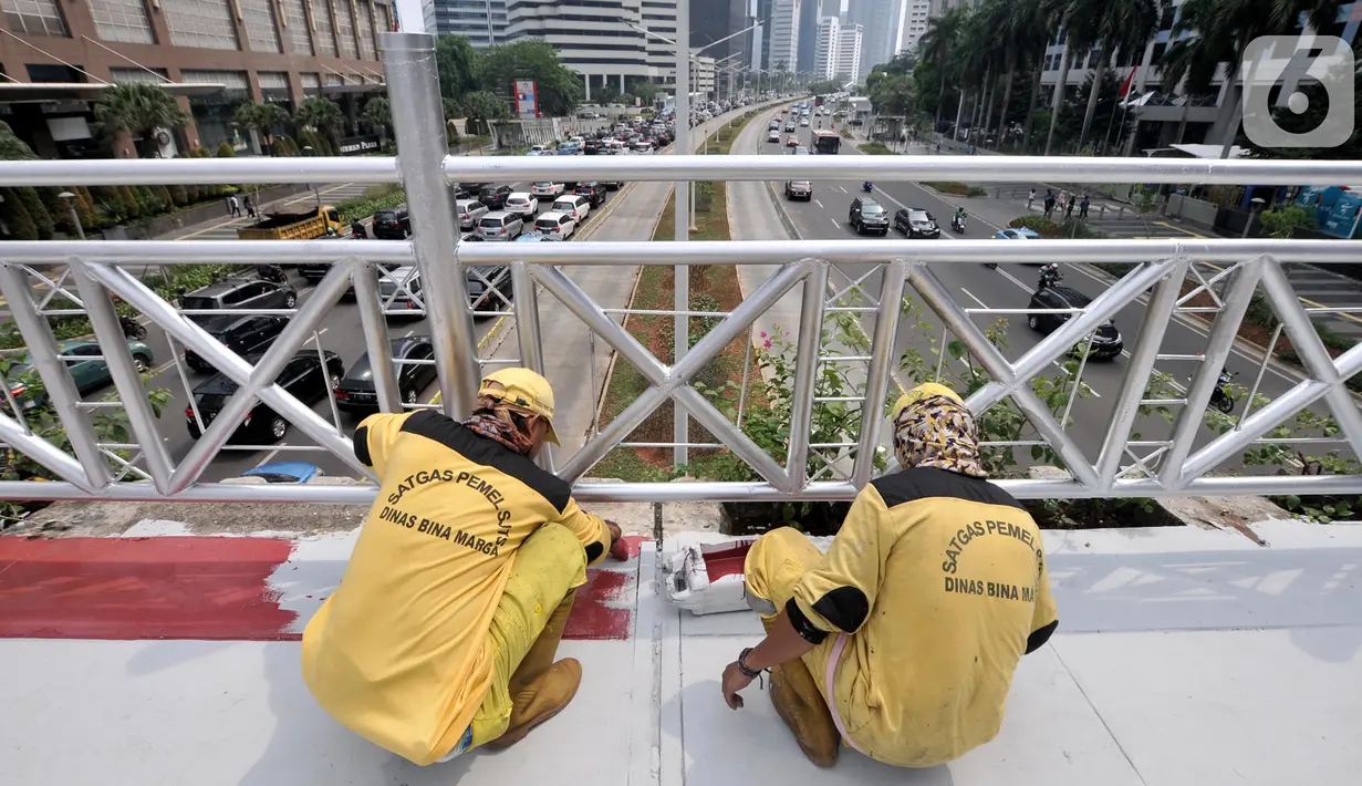 Petugas Bina Marga DKI Jakarta mengecat jembatan penyeberangan orang (JPO) yang tidak beratap di jalan Sudirman, Rabu (6/11/2019). Pemprov DKI melalui Dinas Bina Marga mencopot atap JPO Sudirman agar pejalan kaki dapat menikmati pemandangan gedung-gedung pencakar langit. (merdeka.com/Iqbal Nugroho)