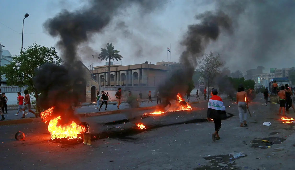 Demonstran antipemerintah melakukan pembakaran saat protes di dekat Alun-Alun Tahrir, Baghdad, Irak, Senin (27/7/2020). Perdana Menteri Irak mengatakan telah memerintahkan penyelidikan atas pembunuhan dua demonstran antipemerintah. (AP Photo/Hadi Mizban)