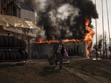 Seorang pria mengambil barang-barang dari toko yang terbakar setelah serangan Rusia di Kharkiv, Ukraina, 25 Maret 2022. (AP Photo/Felipe Dana)