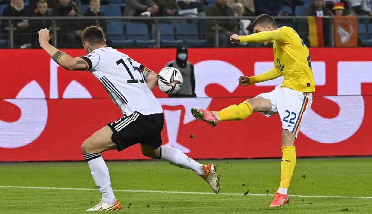 Pemain Jerman Niklas Suele (kiri) berebut bola dengan pemain Rumania Valentin Mihaila pada pertandingan Grup J kualifikasi Piala Dunia Qatar 2022 di Hamburg, Jerman, 8 Oktober 2021. Jerman menang 2-1. (John MACDOUGALL/AFP)