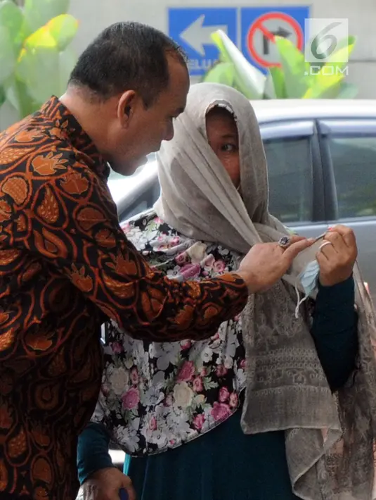 Petugas meminta Kasi Dinkes Bengkulu Selatan Wati membuka kain penutup wajahnya saat tiba di Gedung KPK, Jakarta, Rabu (16/5). Wati terjaring OTT bersama Bupati Bengkulu Selatan Dirwan Mahmud beserta istri mudanya, Heni. (Merdeka.com/Dwi Narwoko)