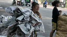 Seorang ibu bersama anaknya mengumpulkan koran yang digunakan sebagai alas, Jatinegara, Jakarta, Rabu (6/7/2016). Usai ribuan warga menunaikan salat Id, tumpukan koran berserakan dimana-mana. (Liputan6.com/Yoppy Renato)
