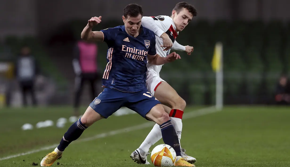 Bek Arsenal, Cedric Soares berebut bola dengan penyerang Dundalk, Jamie Wynne dalam pertandingan Grup B Liga Europa 2020/2021 di Stadion Aviva, Jumat (11/12/2020) dini hari WIB. Arsenal menang 4-2 saat bertandang di markas wakil Irlandia, Dundalk. (Brian Lawless/PA via AP)