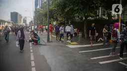 Petugas Satpol PP berjaga saat warga berolahraga pada car free day (CFD) di kawasan Bundaran HI, Jakarta, Minggu (17/11/2019). Usai ditertibkan, tak terlihat satu pun PKL yang berjualan di lokasi tersebut. (Liputan6.com/Faizal Fanani)