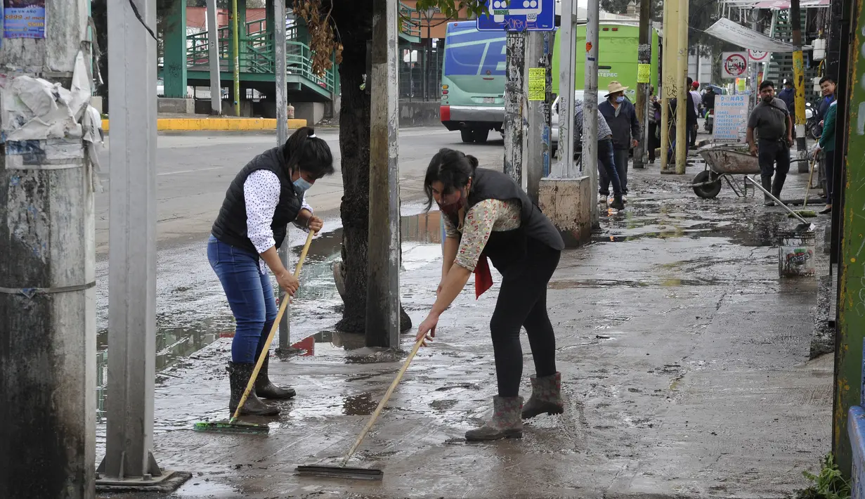 Penduduk desa membuang lumpur dari jalan setelah hujan lebat yang menyebabkan banjir di Ecatepec, Meksiko (7/9/2021).  (AFP/Claudio Cruz)