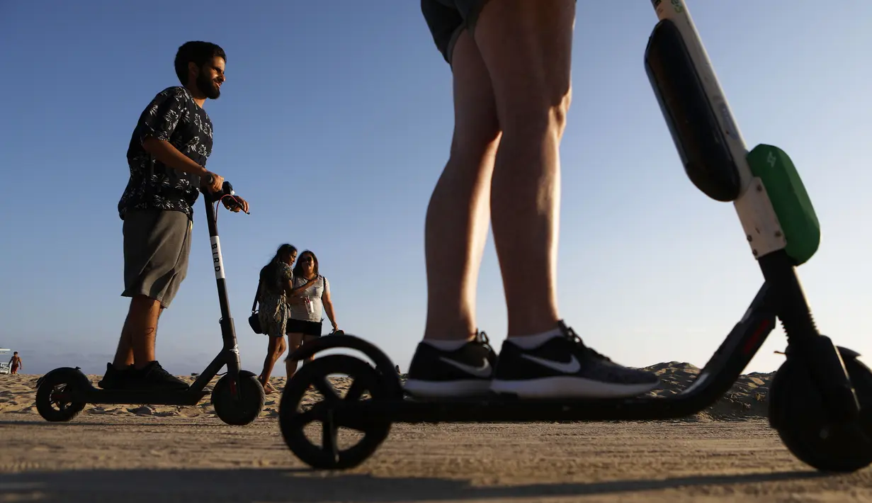 Pengendara menaiki skuter listrik  di sepanjang Venice Beach, Los Angeles, 13 Agustus 2018. Beberapa penduduk kota mengeluhkan skuter-e yang kontroversial karena membahayakan pejalan kaki dan terkadang menyumbat trotoar. (Mario Tama/Getty Images/AFP)