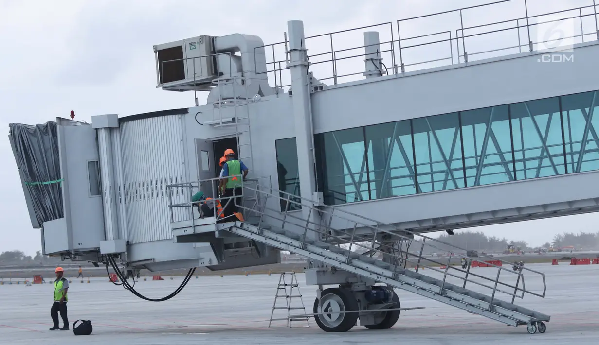 Pekerja mengecek kondisi garbarata yang terpasang di apron Bandara Internasional Yogyakarta di Kabupaten Kulon Progo, DI Yogyakarta, Selasa (23/4). Menurut rencana, khusus Bandara Internasional Yogyakarta ini akan mulai beroperasi pada 29 April mendatang. (Liputan6.com/Helmi Fithriansyah)