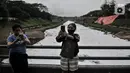 Warga berswafoto dengan latar belakang limbah busa yang memenuhi aliran Kanal Banjir Timur (KBT), Duren Sawit, Jakarta, Kamis (2/7/2020). Penampakan busa akibat limbah pabrik dan rumah tangga sejak dua minggu lalu itu menjadi tontonan warga meski menimbulkan bau tak sedap (merdeka.com/Iqbal Nugroho)