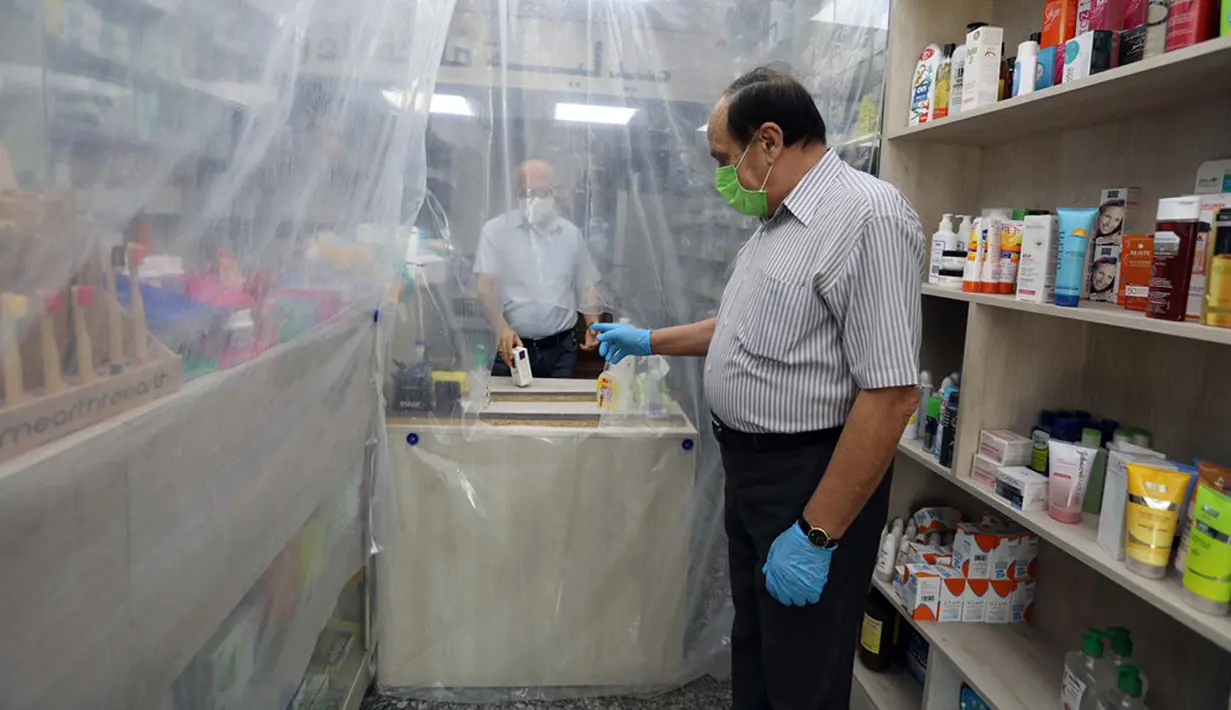 Lapisan plastik digunakan untuk mengurangi kontak fisik antara pegawai dengan pembeli di sebuah apotek di Baghdad, Irak, Selasa (14/4/2020). Menjaga jarak fisik atau physical distancing dinilai langkah paling tepat untuk mengurangi penyebaran virus corona COVID-19. (Xinhua)