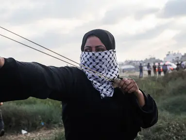 Wanita Palestina memakai ketapel untuk melemparkan batu ke arah pasukan Israel saat bentrok di Khan Yunis, Jalur Gaza, Jumat (13/9/2019). Warga berunjuk rasa dalam aksi damai Great March of Return di Jalur Gaza. (SAID KHATIB/AFP)