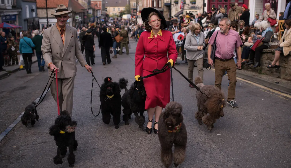 Reenactor Perang Dunia II mengenakan pakaian tahun 40-an membawa anjing saat mengikuti 'Railway in Wartime Event' yang ke 25 di Pickering, Inggris (15/10). (AFP Photo/Oli Scarff)