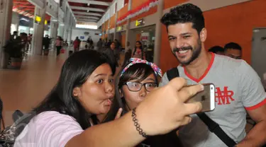 Pemeran Selim ‘Elif’, Emre Kivilcim berselfie dengan fans saat tiba di Bandara Ngurah Rai, Bali, Selasa (25/8/2015). Usai mengisi acara puncak HUT SCTV ke-25, para bintang Elif itu melanjutkan perjalanan berliburnya ke Bali. (Liputan6.com/Herman Zakharia)