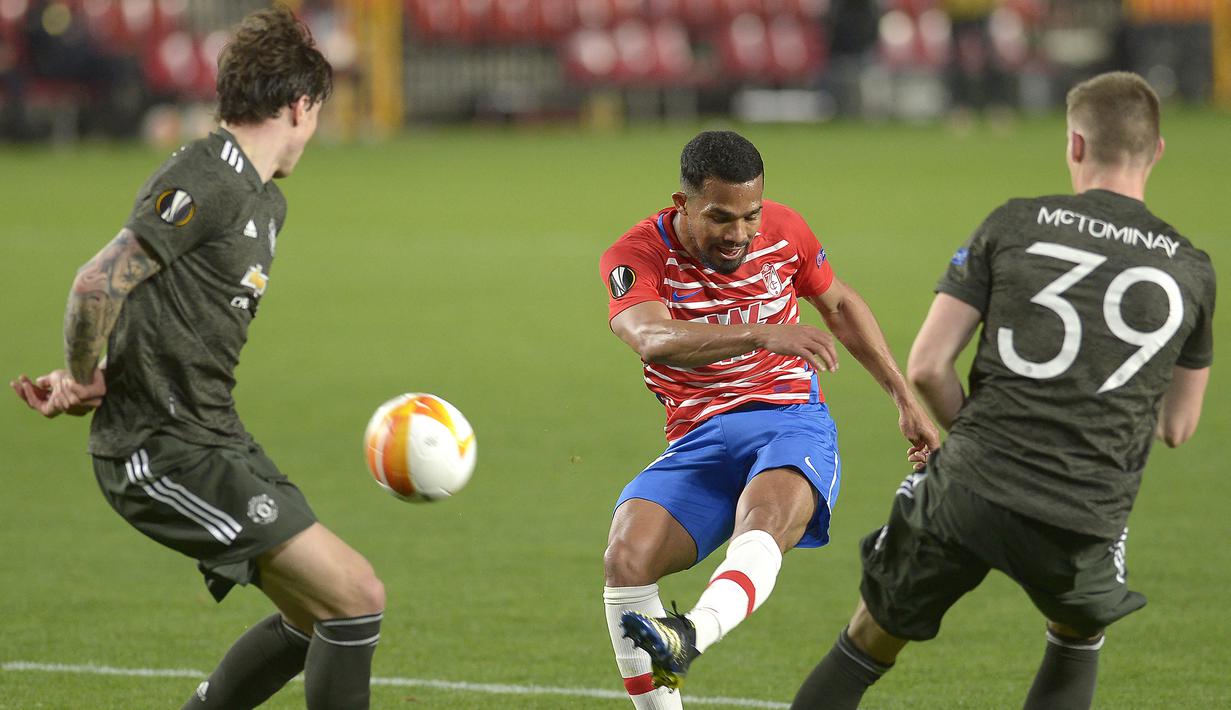 Gelandang Granada, Yangel Herrera (tengah) melepaskan tendangan ke gawang Manchester United dalam laga leg pertama perempatfinal Liga Europa 2020/2021 di Nuevo Los Carmenes Stadium, Granada, Kamis (8/4/2021). Granada kalah 0-2 dari Manchester United. (AFP/Cristina Quicler)