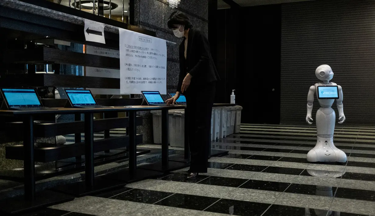 Robot Pepper (kanan) berdiri di lobi hotel yang diubah menjadi lokasi karantina pasien COVID-19, Tokyo, Jepang, Jumat (1/5/2020). Pemerintah Jepang menyewa kamar hotel untuk untuk meringankan beban daya tampung rumah sakit. (Philip FONG/AFP)