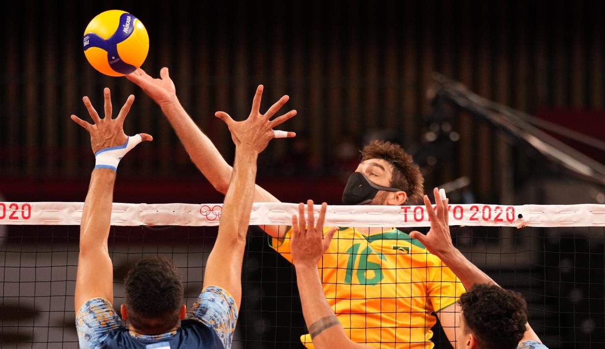 Pevoli Brasil, Lucas Saatkamp melakukan spike ke arah pemain Argentina pada babak penyisihan grup B bola voli putra Olimpiade Tokyo 2020 di Ariake Arena pada 26 Juli 2021. Lucas Saatkamp menggunakan masker saat berlaga demi melindungi dirinya dan keluarganya dari Covid-19. (AP Photo/Frank Augstein)