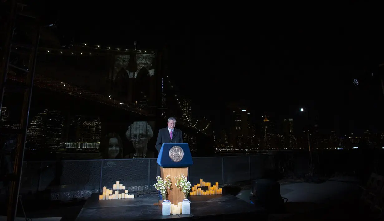Wali Kota New York Bill De Blasio berbicara saat gambar korban diproyeksikan pada Jembatan Brooklyn selama Hari Peringatan COVID-19 di Brooklyn, New York, Amerika Serikat, 14 Maret 2021. Bill De Blasio menggembar-gemborkan pahlawan petugas kesehatan yang menyelamatkan nyawa. (Kena Betancur/AFP)