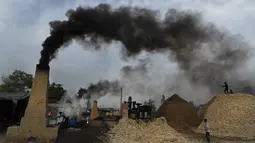 Asap mengepul dari cerobong asap saat pekerja menyiapkan gula merah di pinggiran Bareilly, India, Selasa (23/3/2021).  Jaggery adalah gula tradisional yang tidak dimurnikan yang dikonsumsi di banyak bagian Asia, terbuat dari molase tebu dan nira kurma. (AP Photo/Rajesh Kumar Singh)