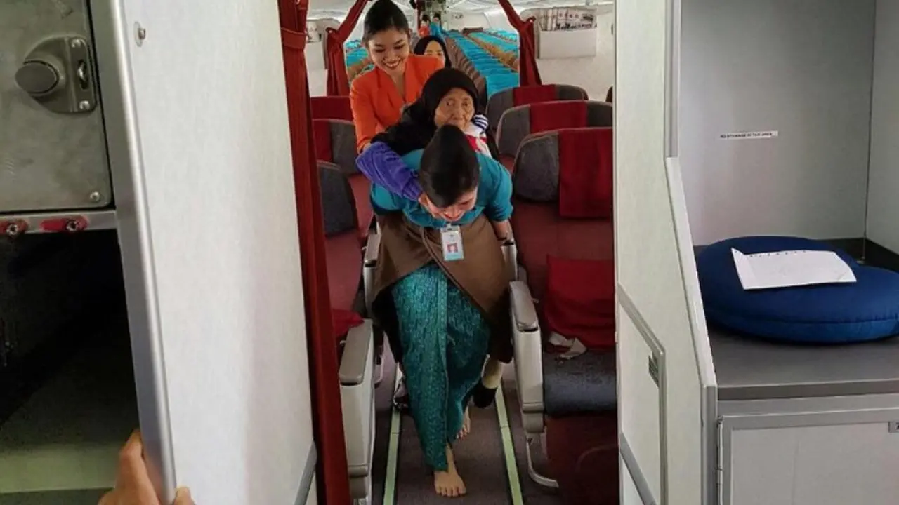 Foto Pramugari Garuda yang Gendong Seorang Nenek di Pesawat