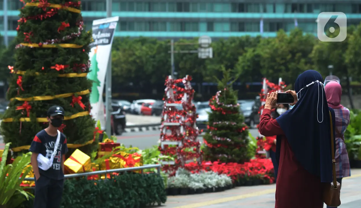 Warga berfoto dengan latar hiasan pohon Natal 2021 di Bundaran HI, Jakarta, Sabtu (25/12/2021). Libur Natal 2021 dimanfaatkan sebagian warga berfoto berlatar pohon Natal yang telah dihias atau berjalan-jalan ke mal untuk mengisi waktu berlibur bersama. (merdeka.com/Imam Buhori)