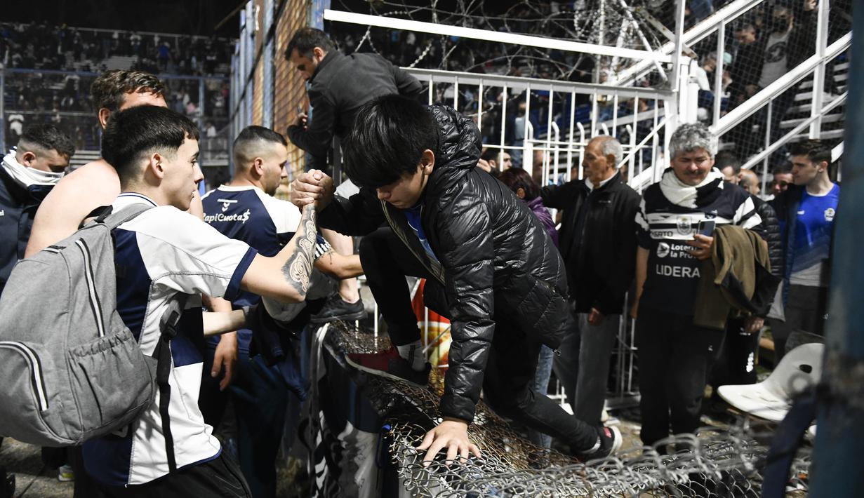 Laga di Stadion Juan Carmelo Zerillo menjadi daya tarik bagi para penonton. Hanya saja, laga harus dihentikan pada menit ke-9 karena situasi menjadi ricuh. Sejumlah penonton pun segera bergegas keluar dari tribune usai polisi menembakan gas air mata dari luar stadion. (AP Photo/Gustavo Garello)