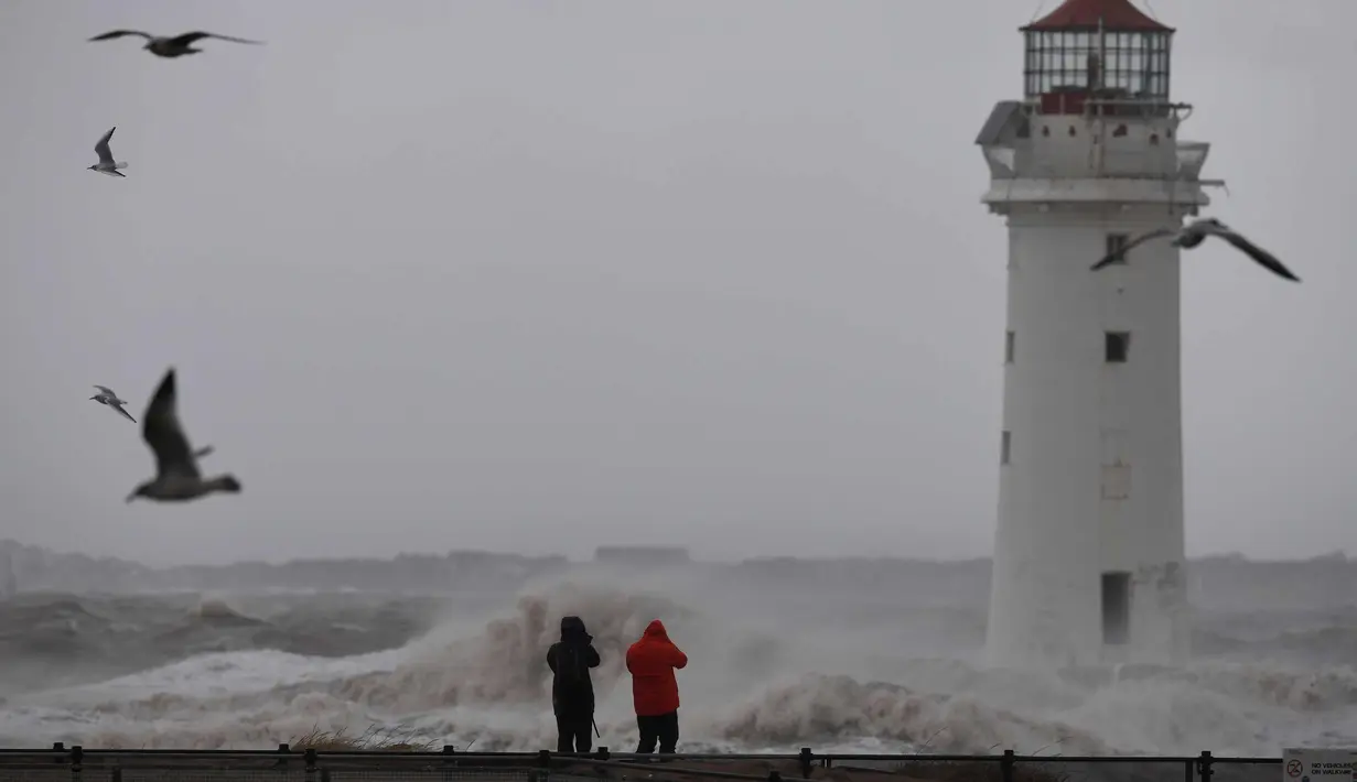 Dua warga mengambil gambar ombak yang disebabkan badai Eleanor di sepanjang pinggir laut di New Brighton, Inggris barat laut (3/1). (AFP Photo/Paul Ellis)