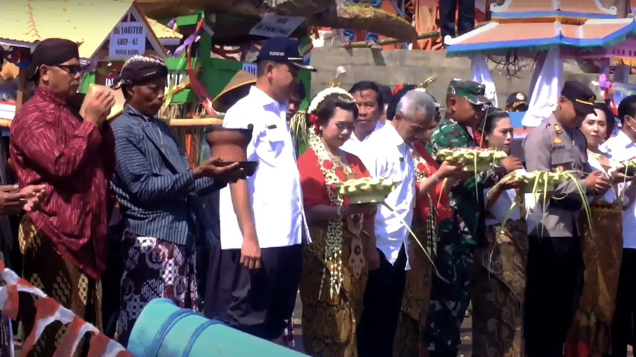 Para Tamu dan warga melabuh hasil bumi di Pantai Baron pada prosesi Upacara Sedekah Laut.