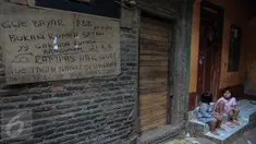 Tulisan protes terhadap penggusuran ditulis di tembok rumah warga di kawasan pemukiman Kampung Pulo, Jakarta Timur, Kamis (23/7). Pemerintah Provinsi DKI Jakarta akan menertibkan bangunan liar yang ada di wilayah Kampung Pulo. (Liputan6.com/Faizal Fanani)