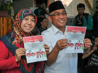 Mohammad Idris dan istri memegang surat suara sebelum melakukan pencoblosan di TPS 077 di Perum Pondok Duta, Depok, (9/12). Idris akan bersaing dengan pasangan nomor urut satu yaitu Dimas Oky Nugroho dan Babai Suhaimi. (Liputan6.com/Yoppy Renato)