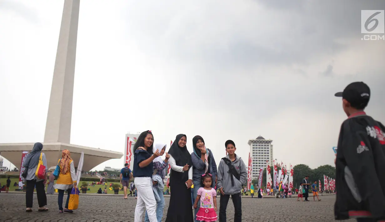 Sejumlah pengunjung berswafoto saat mengunjungi Monumen Nasional (Monas), Jakarta, Sabtu (22/12). Libur sekolah yang berbarengan dengan libur Natal dan Tahun Baru dimanfaatkan masyarakat untuk pergi berwisata ke Monas. (Liputan6.com/Faizal Fanani)