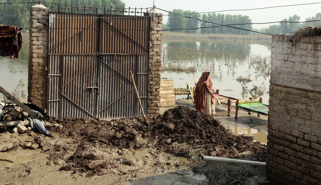 Seorang wanita berjalan di dekat rumah yang rusak setelah hujan lebat, di Charsadda, Pakistan, Rabu (31/8/2022). Para pejabat di Pakistan menyampaikan kekhawatiran Rabu atas penyebaran penyakit yang ditularkan melalui air di antara ribuan korban banjir saat air banjir dari hujan monsun yang kuat mulai surut di banyak bagian negara. (AP Photo/Mohammad Sajjad)