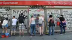 Sejumlah warga membersihkan jendela bank dari coretan aksi protes KTT G20 di Hamburg, Jerman, Minggu (9/7). Demonstrasi yang mewarnai gelaran KTT G20 di Hamburg sejak Kamis waktu setempat itu menyebabkan sejumlah kerusakan. (Christof Stache/AFP)