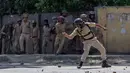 Polisi India melemparkan batu saat bentrok dengan mahasiswa Kashmir di Srinagar, Kashmir yang dikuasai India, (23/5). Bentrokan telah meningkat setelah tentara menggerebek sebuah perguruan tinggi di kota selatan Pulwama bulan lalu. (AP Photo/Dar Yasin)