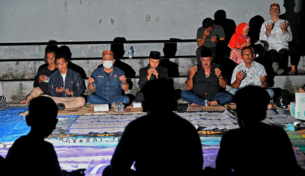 Sejumlah warga menghadiri upacara doa pada malam peringatan 17 tahun tsunami Boxing Day 2004 di monumen Kapal Tsunami Lampulo di Banda Aceh (25/12/2021). (AFP/Chaideer Mahyuddin)