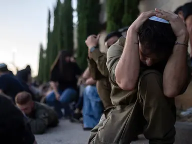 Warga berlindung ketika sirene memperingatkan akan adanya roket yang ditembakkan dari Jalur Gaza, saat pemakaman pria Israel Sagiv Ben Svi, yang dibunuh oleh militan Hamas saat menghadiri festival musik, di pemakaman di Holon, Israel, Kamis (26/10/2019). Lebih dari 1.400 orang tewas dan lebih dari 200 orang ditawan dalam serangan multifront oleh kelompok militan yang menguasai Gaza pada 7 Oktober. (AP Photo/Petros Giannakouris)