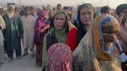 Keluarga Afghanistan berkumpul untuk menerima bahan makanan yang didistribusikan oleh organisasi Kristen yang berbasis di Islamabad di pinggiran Chaman, sebuah kota perbatasan di provinsi Baluchistan barat daya Pakistan, Selasa (31/8/2021). (AP Photo)