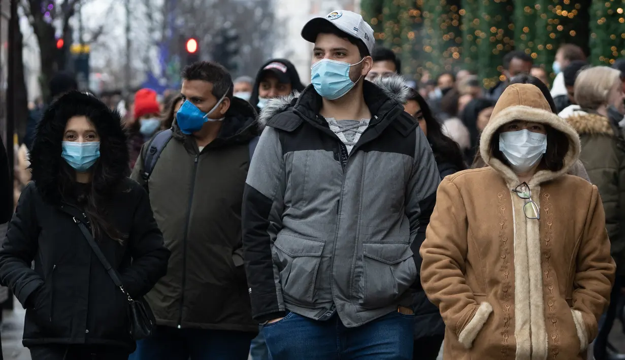 Pembeli, beberapa mengenakan masker, mengantre untuk memasuki department store Selfridges menjelang penjualan Boxing Day di pusat kota London, Minggu (26/12/2021).  'Boxing Day' adalah hari saat toko-toko di Inggris menggelar diskon besar-besaran, sehari setelah Natal. (Niklas HALLE'N / AFP)