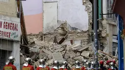Petugas pemadam kebakaran terlihat berada dekat bangunan yang runtuh di kota Marseille, selatan Prancis, Senin (5/11). Kuat dugaan insiden runtuhnya bangunan tersebut karena sudah tua dan dalam kondisi rusak. (AP/Claude Paris)