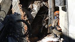Seorang petugas pemadam kebakaran memeriksa sebuah rumah yang rusak akibat ambruknya gedung berlantai empat di dekatnya di kawasan kumuh Rio das Pedras, Rio de Janeiro, Brasil (3/6/2021). Bangunan runtuh merusak pemukiman warga di sekitarnya. (AP Photo/Bruna Prado)