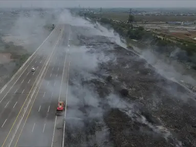 Foto udara kondisi asap dari sisa kebakaran Tempat Pembuangan Sampah (TPS) Ilegal di samping Tol Cibitung-Cilincing, Desa Sumber Jaya, Tambun Utara, Kabupaten Bekasi, Jawa Barat, Senin (25/9/2023). (merdeka.com/Imam Buhori)