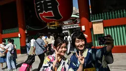 Dua wanita mengenakan kimono berpose di pintu masuk kuil Sensoji di distrik Asakusa Tokyo (22/9/2020). Kuil tersebut masih berdiri kokoh dan menjadi salah satu destinasi wajib para wisatawan yang datang ke Tokyo. (AFP/Charly Triballeau)